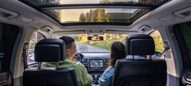 Mit dem eigenen Auto Europa bereisen Ein Mann und eine Frau fahren in einem Auto mit einem Sonnendach