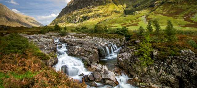 Ein Fluss fließt durch ein Tal mit Bergen im Hintergrund