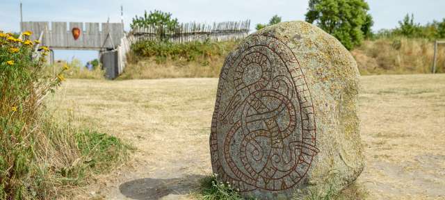 ©Barbara Harbecke Ein großer Stein steht in einem Feld neben einem Holztor