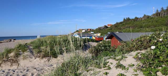Feiner Sandstrand: Dänemark Ein Strand mit bunten Hütten im Hintergrund
