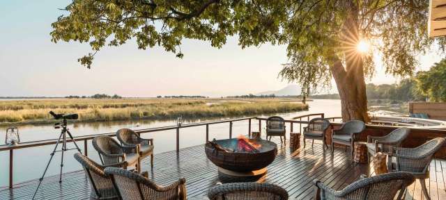 Aussichtsdeck Ein Holzdeck mit Stühlen und einem Feuer
