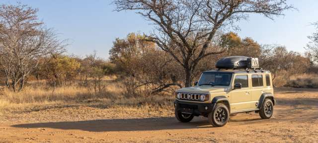 Ein brauner suzuki-jeep fährt auf einer unbefestigten straße