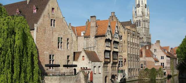 Hansestadt Brügge: Rozenhoedkaai Eine Reihe von Gebäuden neben einem Fluss mit einem Turm dahinter