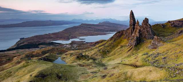 Ein Berg mit einem Felsen darauf und einem See im Hintergrund
