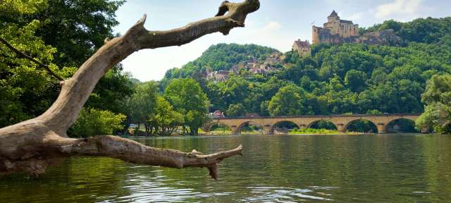 Kultur am Fluss: Dordogne Eine Brücke über einen Fluss mit einem Schloss im Hintergrund