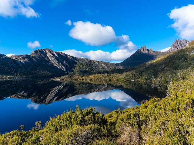 Ein See mit Bergen im Hintergrund und einem blauen Himmel mit Wolken