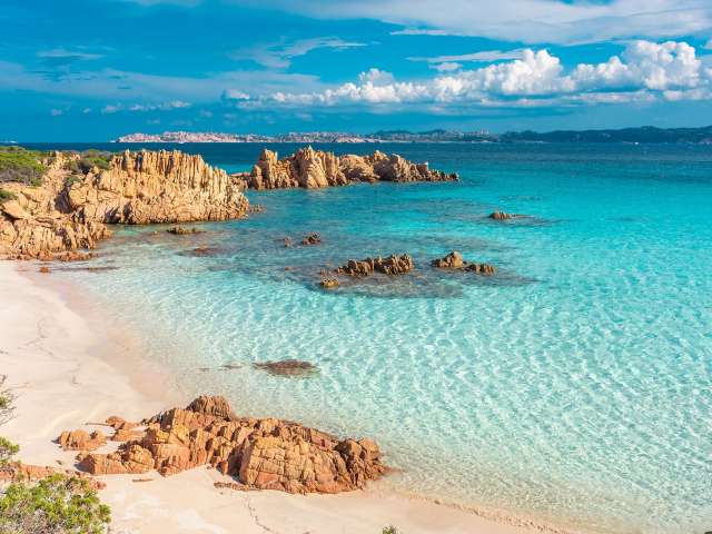 Ein Strand mit weißem Sand und blauem Wasser