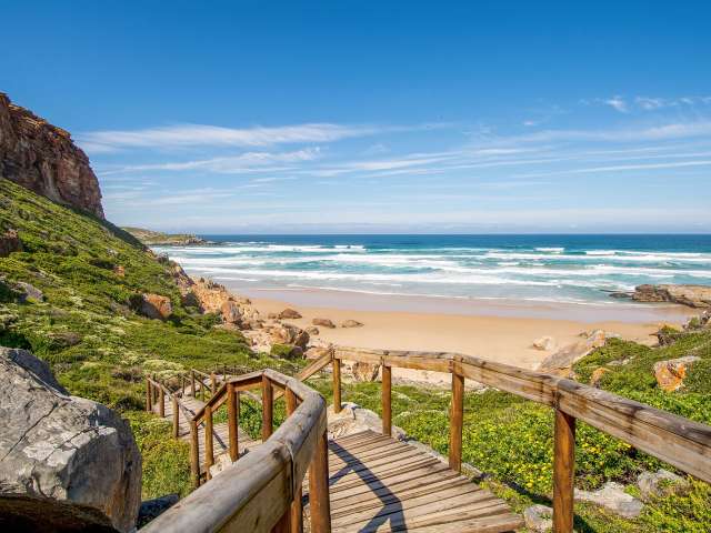 Eine Holztreppe führt hinunter zu einem Strand