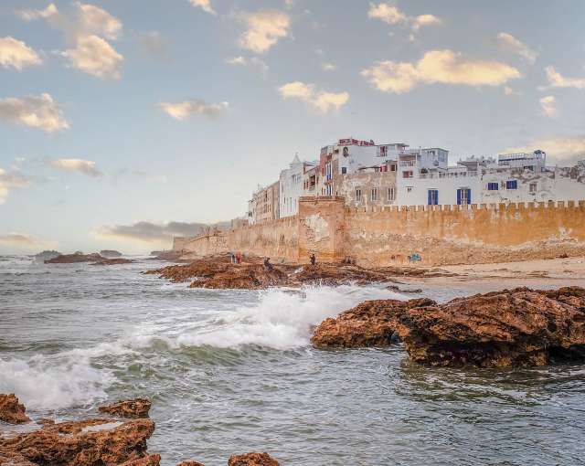 Wellen brechen an einem felsigen Strand in der Nähe eines weißen Gebäudes