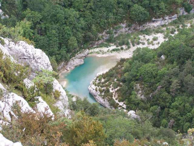 Der Blick von oben auf eine türkisfarbene Schlucht mit bewaldeten Hängen und Felsen.