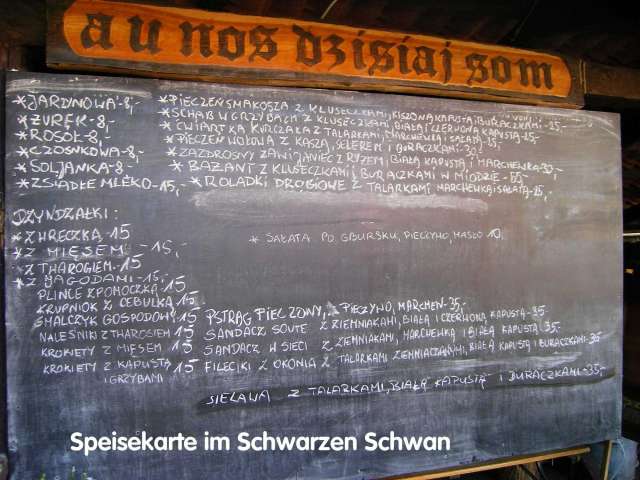 Das Bild zeigt eine Tafel mit einer Speisekarte in weißer Schrift auf schwarzem Grund, die im oberen Bereich durch eine braune Holzverkleidung mit dem Titel "a u nos dzisiaj som" ergänzt wird.