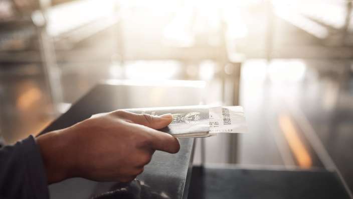 Eine Person hält einen Pass und einen Flugticket in der Hand