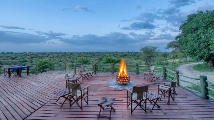 Ein Holzdeck mit Stühlen und einem Feuer darauf