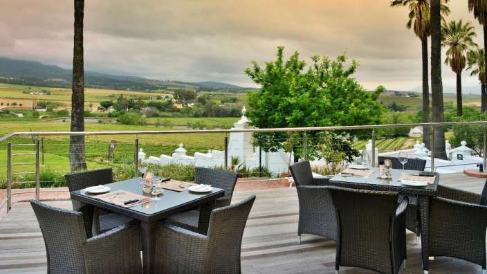 Tische und Stühle auf einem Balkon mit Blick auf einen Weinberg