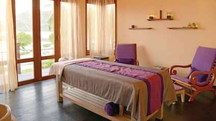 Ein Raum mit einem Massagetisch , Stühlen und Fenstern .