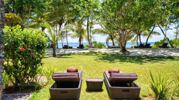 Zwei Liegestühle mit Handtüchern auf ihnen stehen auf einem grünen Rasen