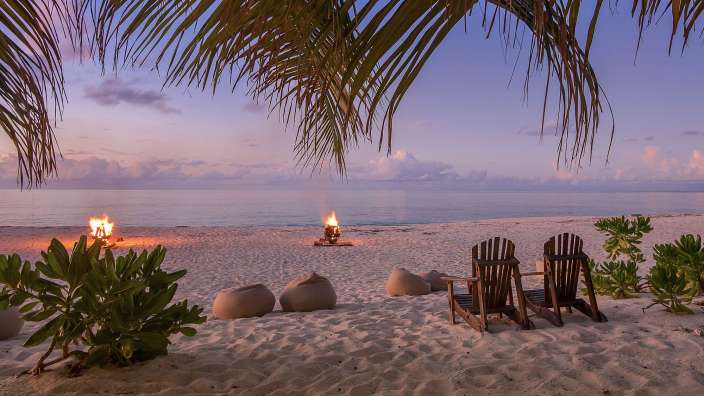 Ein Strand mit Stühlen und einem Feuer im Hintergrund