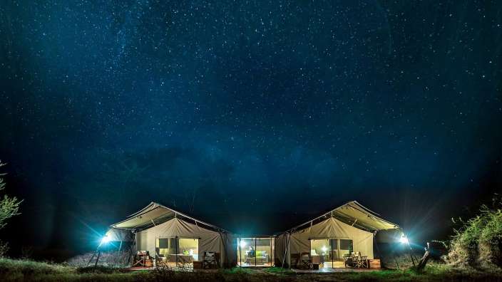 Zwei Zelte stehen unter einem Sternenhimmel