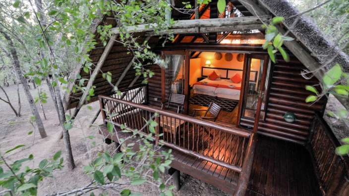 Ein kleines Holzhaus mit einem Balkon und einem Bett darauf