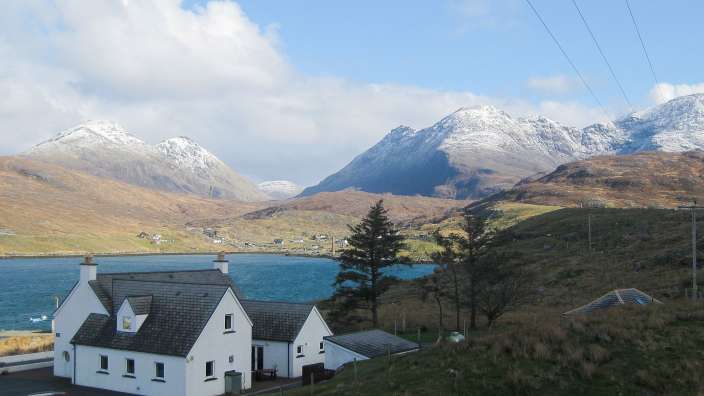 Ein weißes Haus mit einem See und schneebedeckten Bergen im Hintergrund