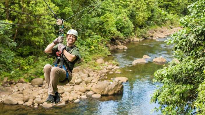 Eine Person fährt auf einer Seilbahn über einen Fluss
