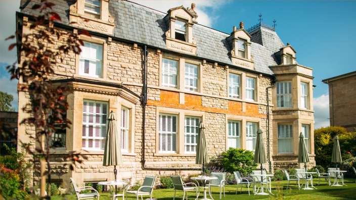 Ein großes Steingebäude mit Tisch und Stühlen vorne