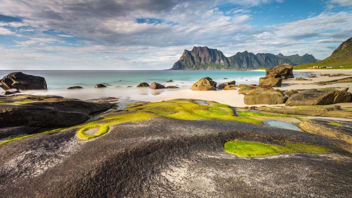 Ein felsiger Strand mit Bergen im Hintergrund