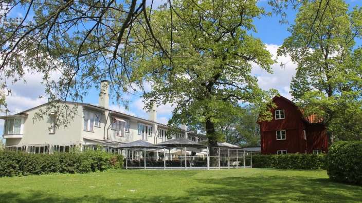 Ein weißes Gebäude mit einem roten Gebäude dahinter
