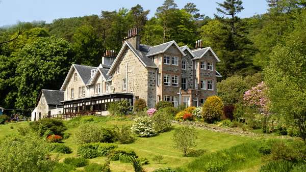 Ein großes Steinhaus sitzt auf einem Hügel inmitten von Bäumen