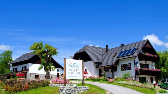 Ein weißes Haus mit einem Schild davor, das sagt " plitvice miric inn "