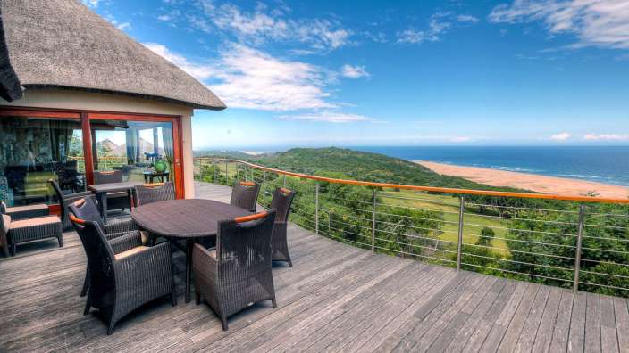 Ein Tisch und Stühle auf einem Holzdeck mit Blick auf das Meer