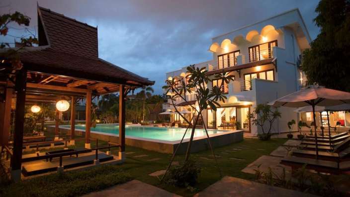 Ein großes weißes Gebäude mit einem Pool im Vordergrund