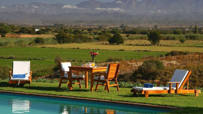 Ein Tisch und Stühle neben einem Pool mit Bergen im Hintergrund
