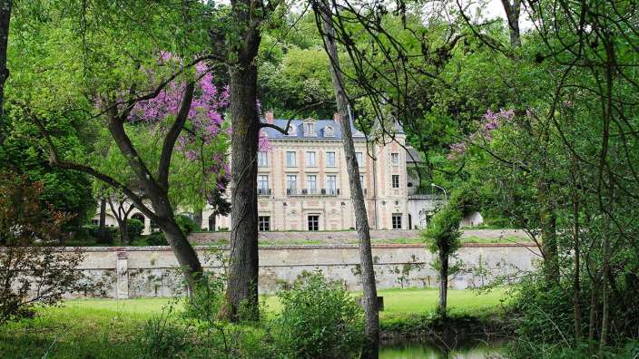 Ein großes Gebäude inmitten eines Waldes mit einem Fluss im Vordergrund
