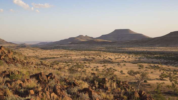 Eine Wüste mit Bergen im Hintergrund und einem blauen Himmel