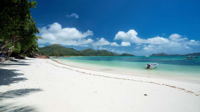 Ein weißes Boot schwimmt in einem türkisfarbenen Ozean