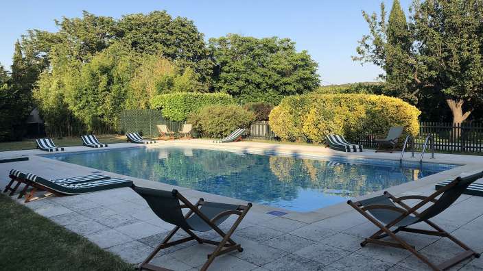 Liegestühle stehen um einen großen Swimmingpool