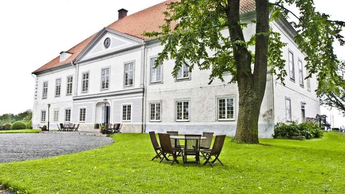 Ein großes weißes Gebäude mit einem Tisch und Stühlen davor