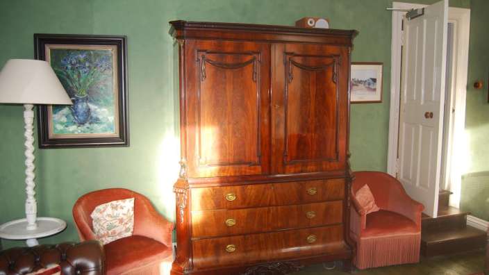 Ein Wohnzimmer mit grünen Wänden und einem großen Holzschrank