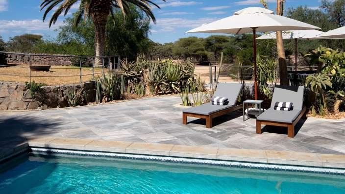 Ein Swimmingpool mit Liegestühlen und Sonnenschirmen umgeben