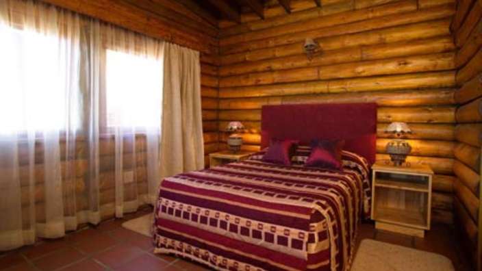 Ein Schlafzimmer in einem Blockhaus mit einem Bett und zwei Nachttischen