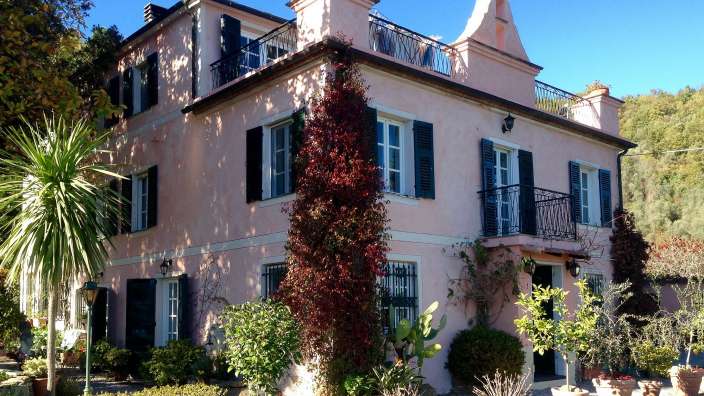 Ein großes rosa Haus mit schwarzen Fensterläden