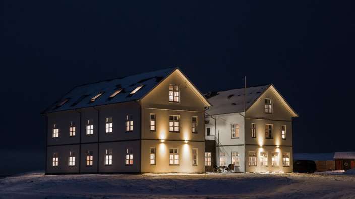 Ein großes weißes Gebäude mit vielen Fenstern in einem schneebedeckten Feld