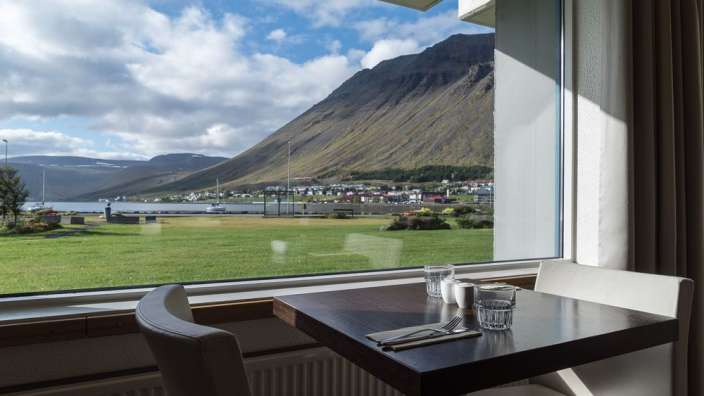 Ein Tisch und Stühle vor einem Fenster mit einem Berg im Hintergrund