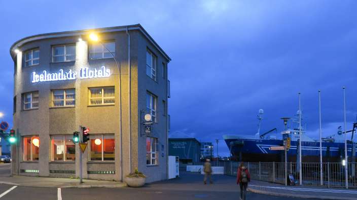 Eine Frau geht in der Nähe eines Gebäudes mit der Aufschrift icelandic hotels