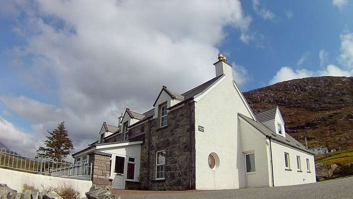 Ein großes weißes Haus mit einem Steingebäude dahinter