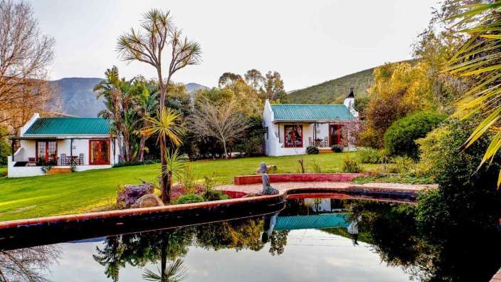 Ein weißes Haus mit einem grünen Dach steht neben einem Teich