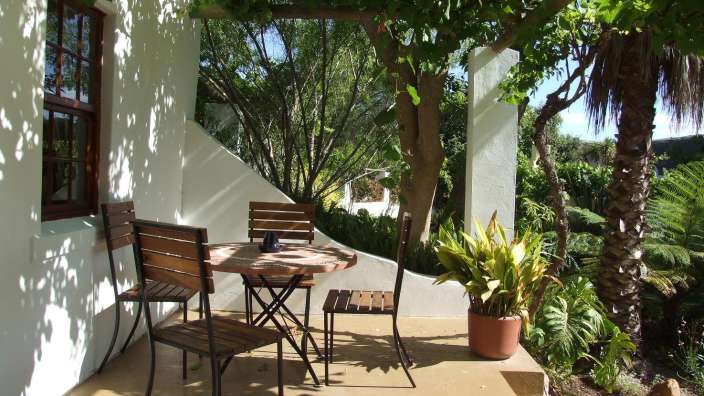 Ein Tisch und Stühle auf einer Terrasse neben einem Baum