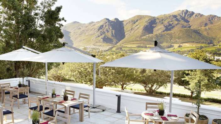 Tische und Stühle auf einer Terrasse mit Blick auf die Berge