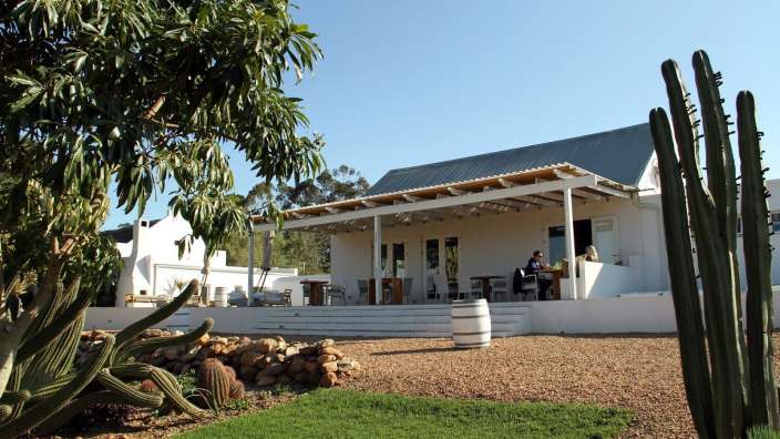 Ein Mann sitzt an einem Tisch vor einem weißen Haus